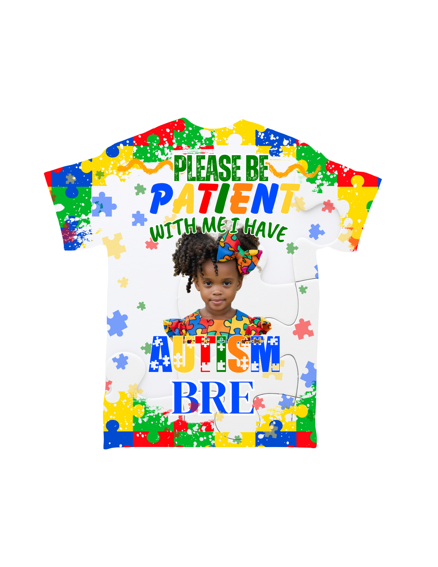 A custom-designed "Cartoon Character All-Over T-Shirt" from Crafty Brown Girl features a puzzle piece pattern and an image of a smiling girl. The text reads, "PLEASE BE PATIENT WITH ME I HAVE AUTISM," with the name "BRE" below. The shirt showcases vibrant blue, yellow, green, and red colors.
